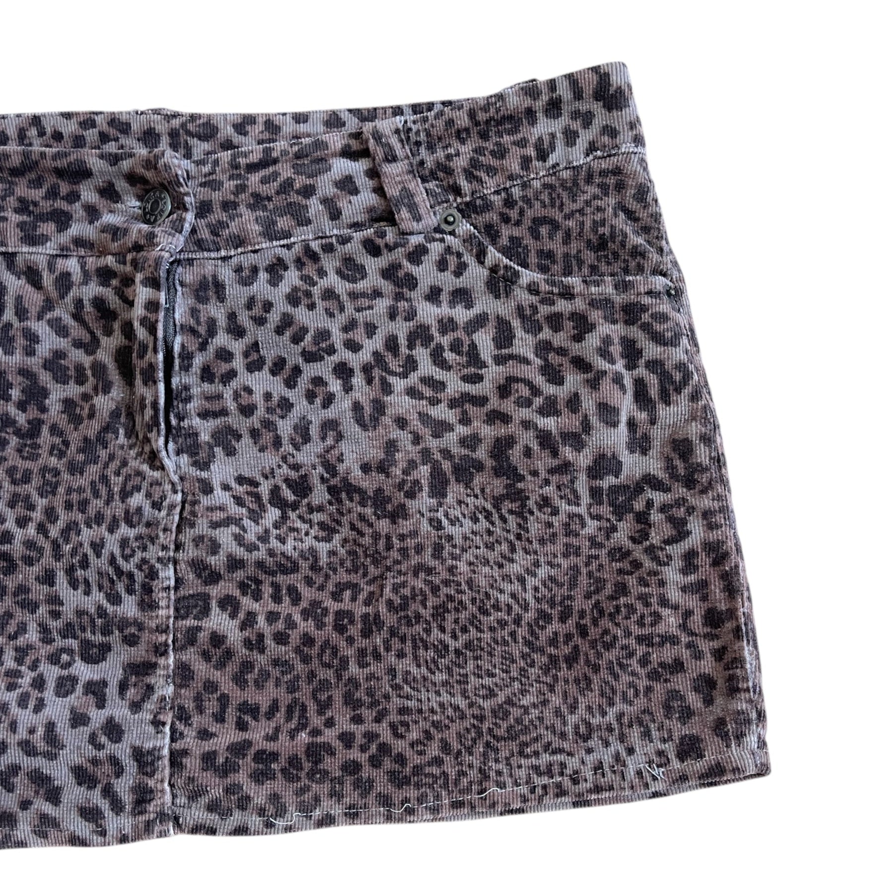 Mini-jupe à imprimé léopard, coupe droite et texture douce. Se ferme par un bouton et une braguette zippée, et dispose de poches à l’avant et à l’arrière.