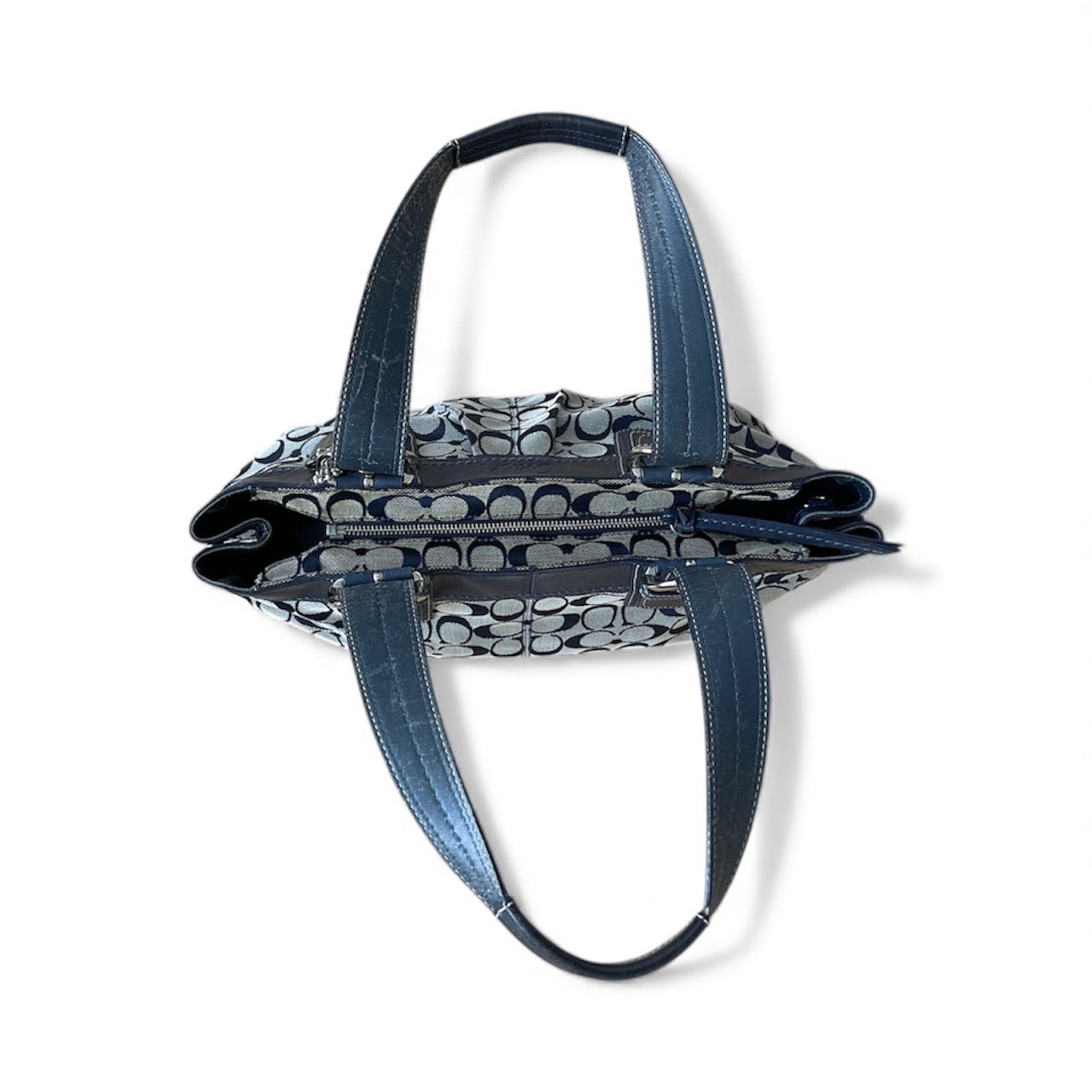 Sac à main Coach vintage en toile monogrammée beige et cuir noir, avec deux anses et boucles argentées, format moyen élégant.