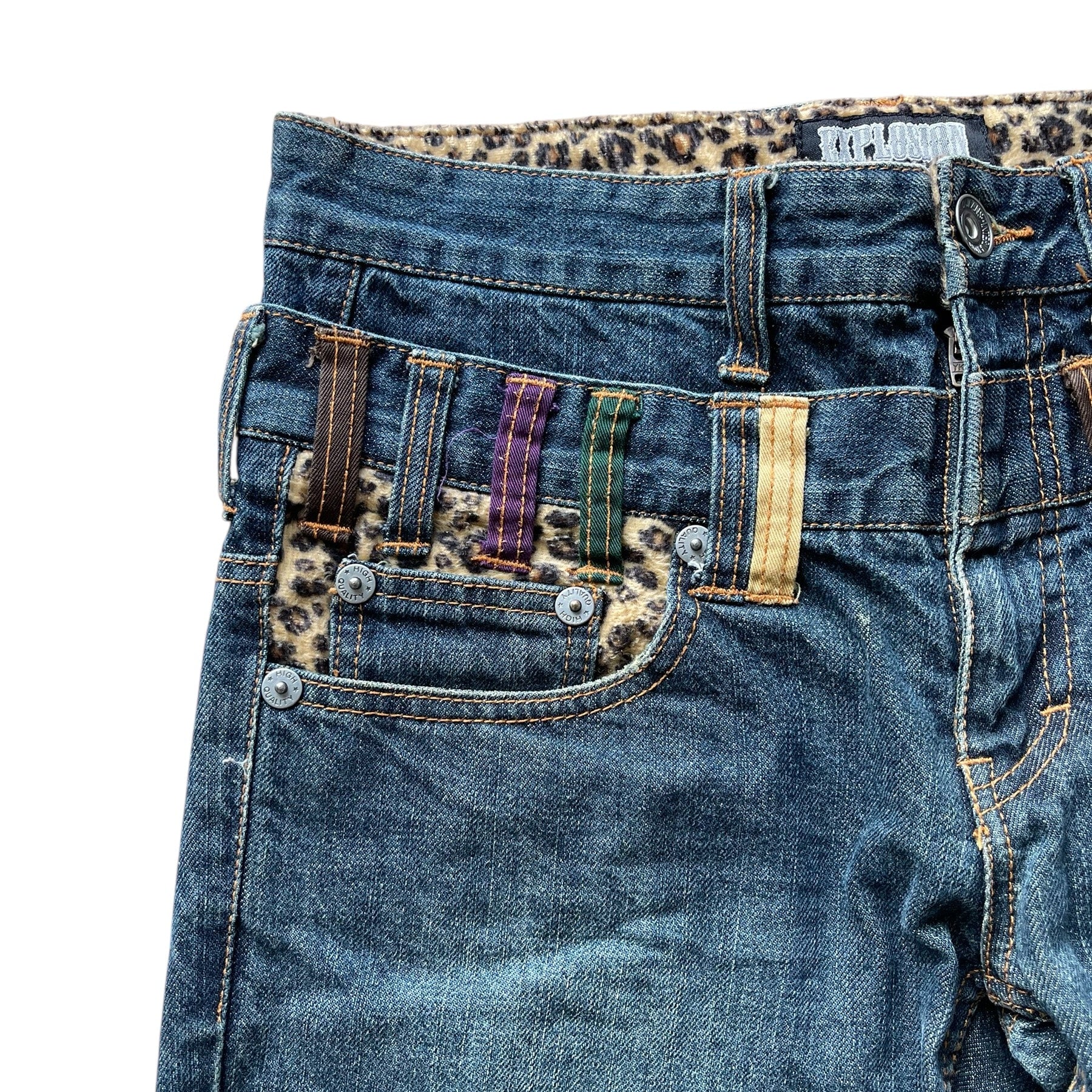 Jean 3/4 en denim bleu vieilli avec déchirures et passants de ceinture multicolores à motif cheetah.