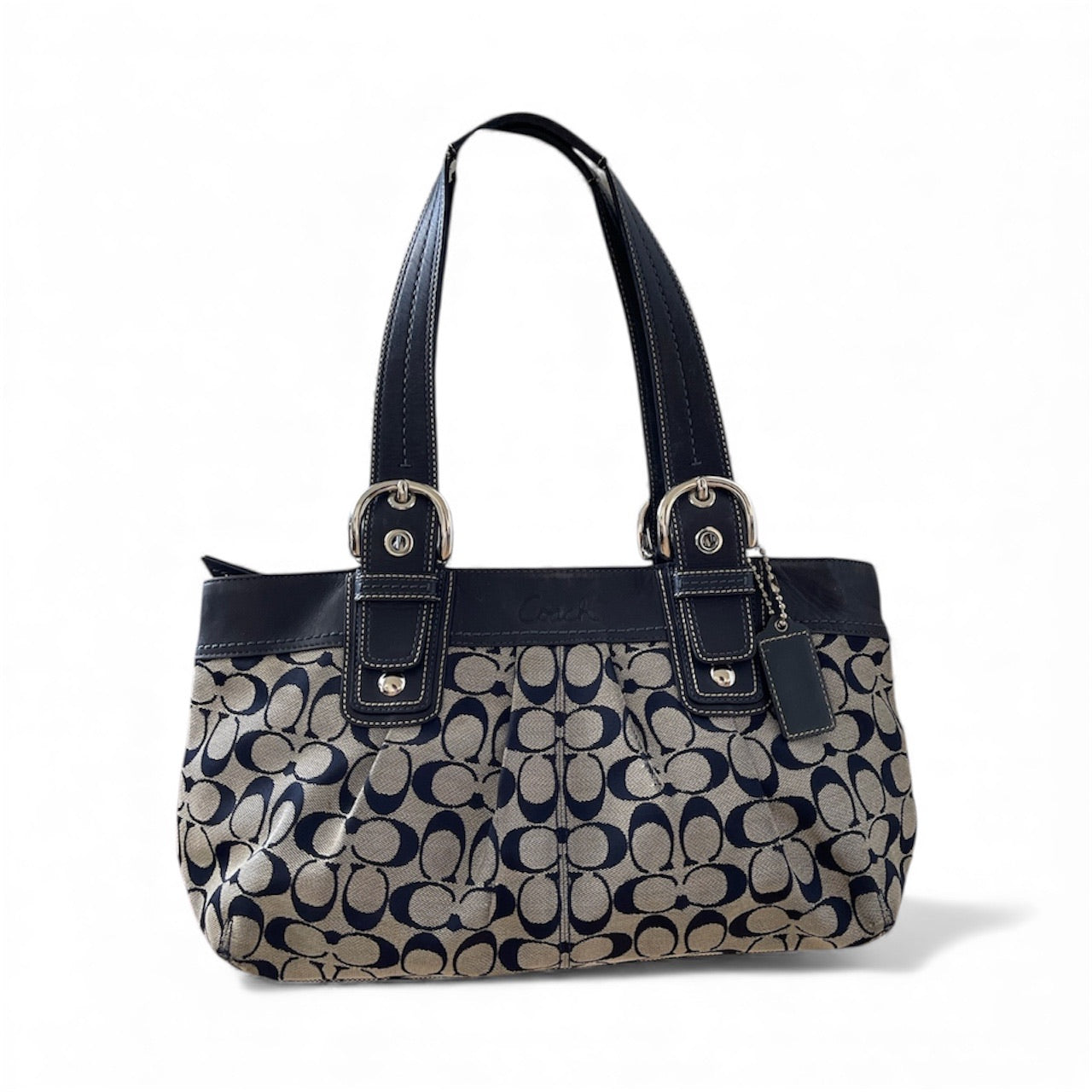 Sac à main Coach vintage en toile monogrammée beige et cuir noir, avec deux anses et boucles argentées, format moyen élégant.