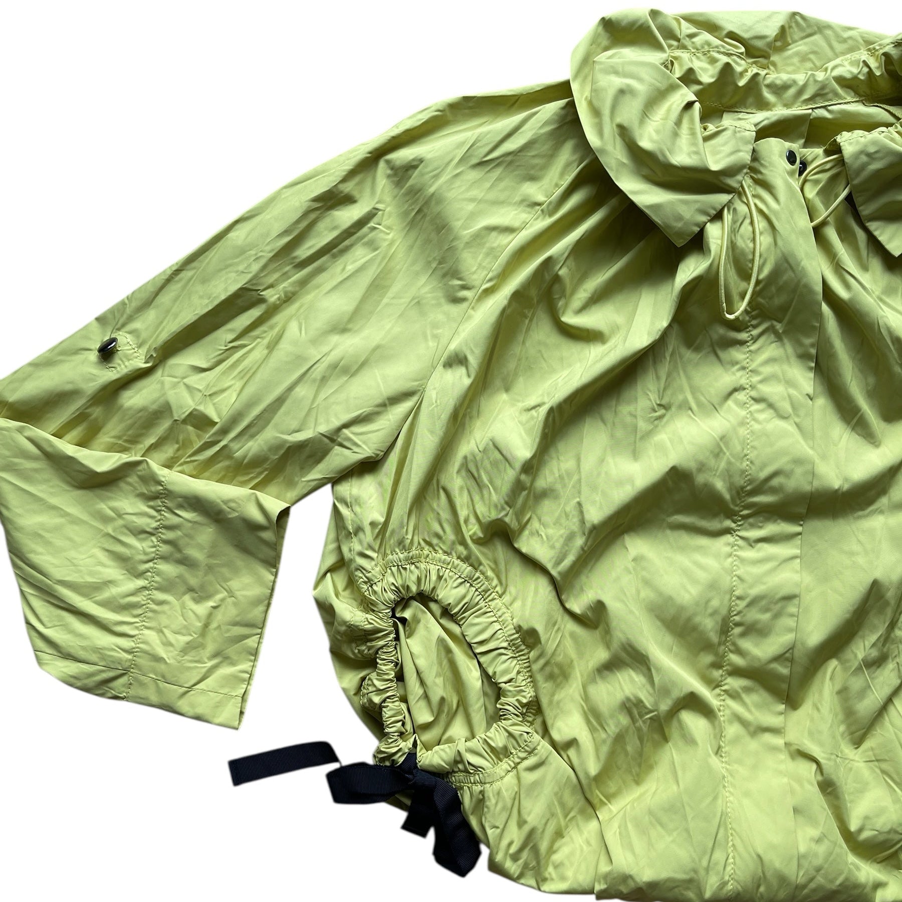 Veste coupe-vent vert anis légère avec col montant, manches longues et cordons noirs pour resserrer la taille.